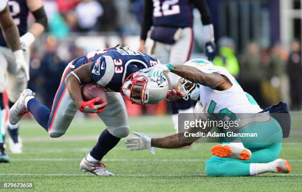 Dion Lewis of the New England Patriots is tackled by Xavien Howard of the Miami Dolphins during the third quarter of a game at Gillette Stadium on...