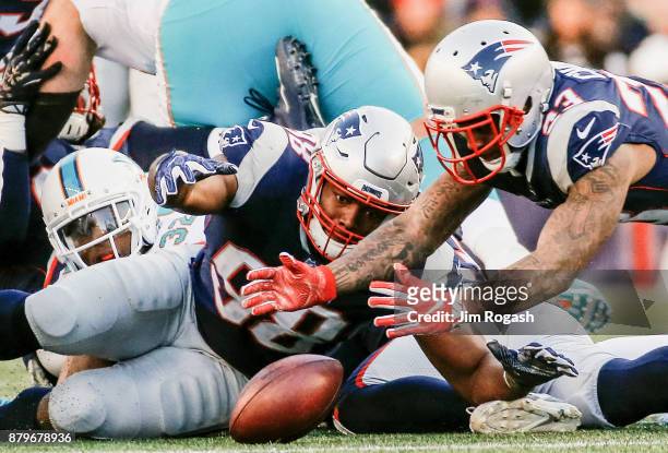 Trey Flowers and Kyle Van Noy of the New England Patriots recover a fumble during the third quarter of a game against the Miami Dolphins at Gillette...