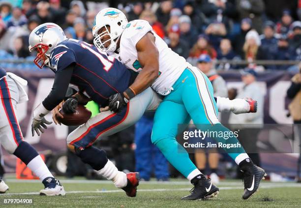 Tom Brady of the New England Patriots is sacked by Cameron Wake of the Miami Dolphins during the fourth quarter of a game at Gillette Stadium on...