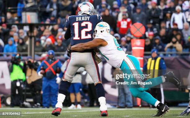 Tom Brady of the New England Patriots is sacked by Cameron Wake of the Miami Dolphins during the fourth quarter of a game at Gillette Stadium on...