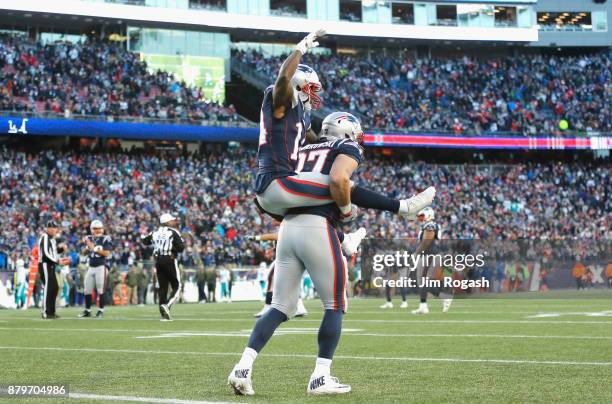 Rob Gronkowski carries Brandin Cooks of the New England Patriots after a touchdown during the fourth quarter of a game against the Miami Dolphins at...