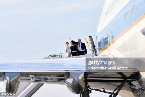 President Donald Trump waves with his wife Melania and son Barron as they board Air Force 1 in Palm Beach, Florida on November 26, 2017 on their way...