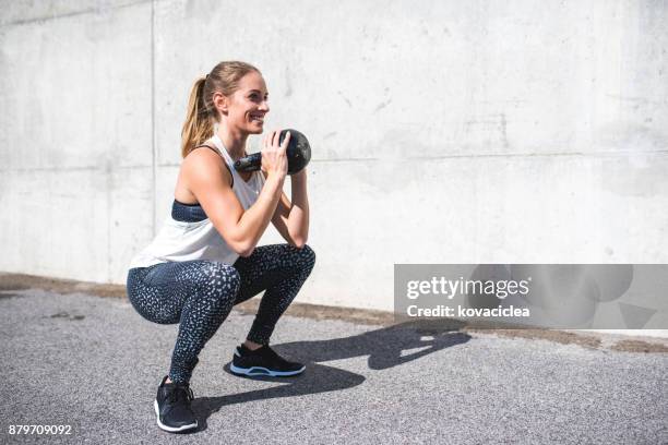 frau macht kniebeugen mit einer kettlebell - hockend stock-fotos und bilder