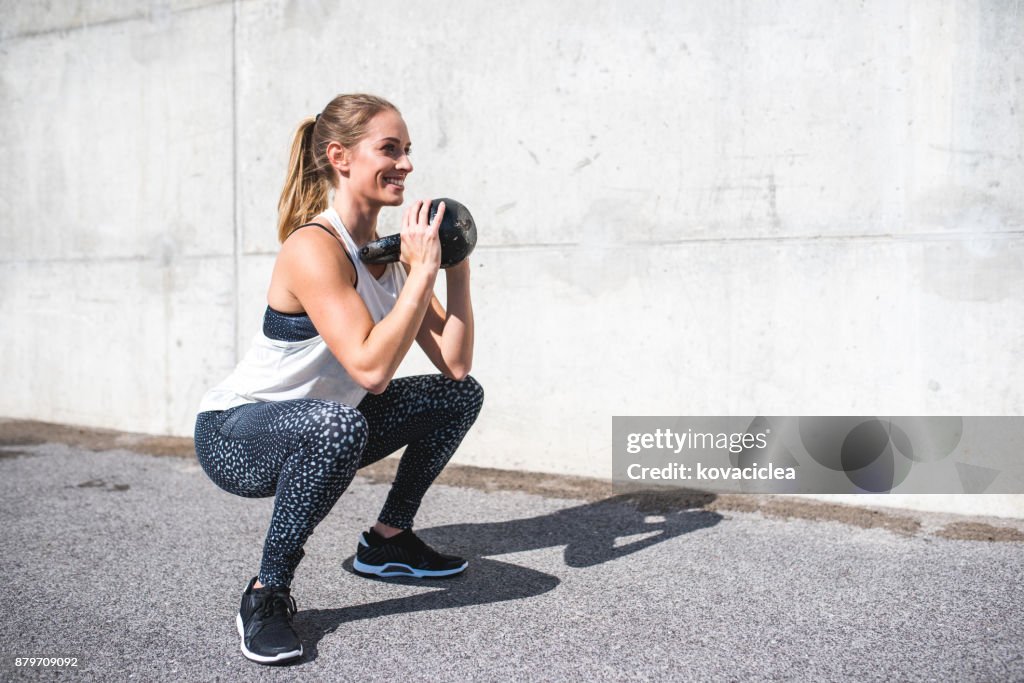 Woman doing squats with a kettlebell