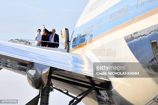 President Donald Trump waves with his wife Melania and son Barron as they board Air Force 1 in Palm Beach, Florida on November 26, 2017 on their way...