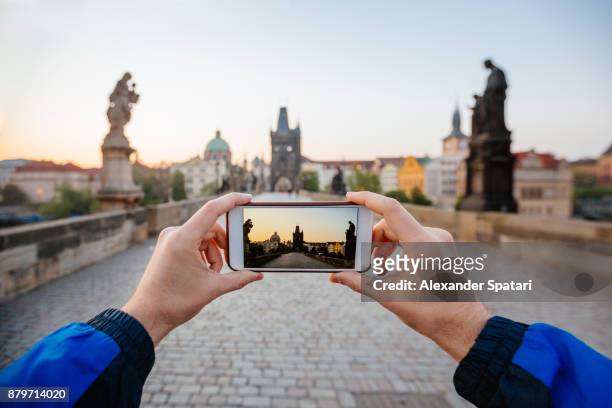 personal perspective view of man taking pcitres with his phone of charles bridge, prague, czech republic - stare mesto stock-fotos und bilder