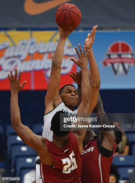 Shavar Newkirk and James Demery of the Saint Joseph's Hawks guard Justin Strings of the Sacramento State Hornets as he goes for a basket in the...