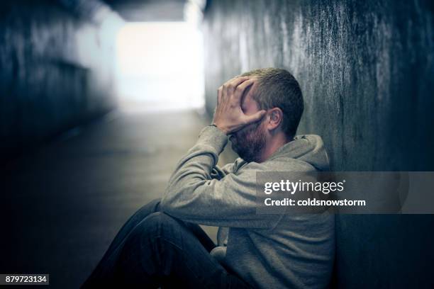 junge obdachlose kaukasischen männchen sitzen in dunkle u-bahn-tunnel - drug addict stock-fotos und bilder