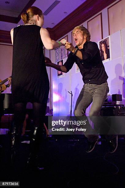 Derek Hough of The Ballas-Hough band dances with a lady from the audience as his band performs onstage inside the Indy 500 race after party at The...