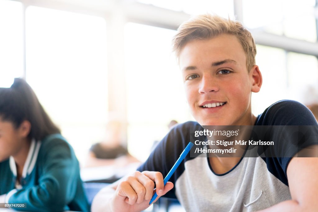 Smiling male teenage student sitting in classroom