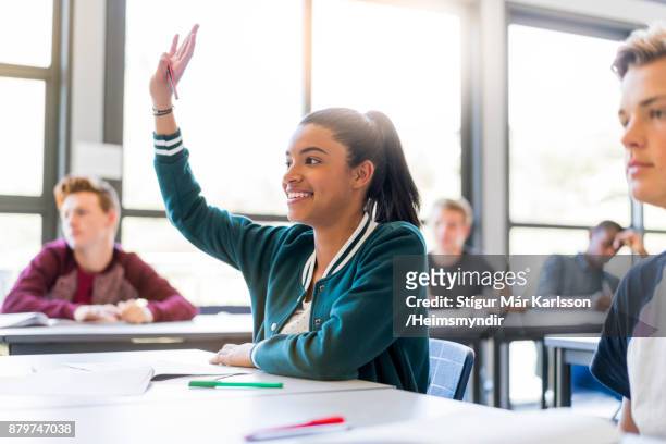 lachende tiener student verhogen hand in klaslokaal - armen omhoog stockfoto's en -beelden