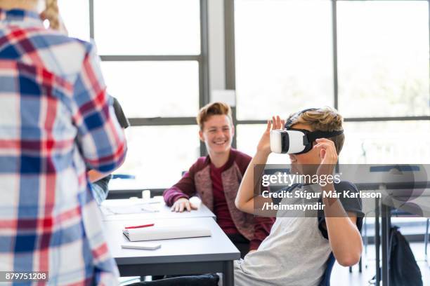 boy wearing virtual reality headset amidst friends - virtual reality classroom stock pictures, royalty-free photos & images