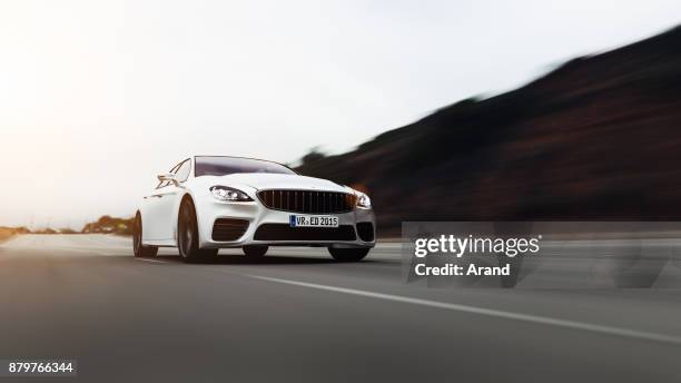 car driving on a road by sea - sport car stock pictures, royalty-free photos & images