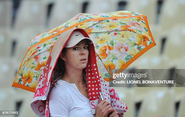 Kazakhstan's Galina Voskoboeva shelters under an umbrella during play against India's Sania Mirza during the French Open tennis second round match on...