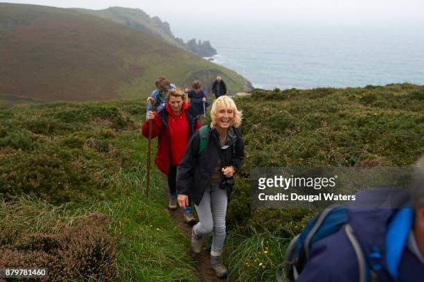 senior hiking group walking along coastal path and laughing. - ir detrás fotografías e imágenes de stock