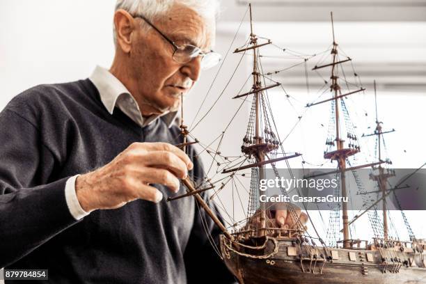 active senior man constructing a boat model - toy sailboat stock pictures, royalty-free photos & images