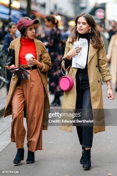 Guest wears a cap, an orange turtleneck top, a brown coat, brown flare cropped pants, black shoes, holds a starbucks coffee cup ; a guest wears a...