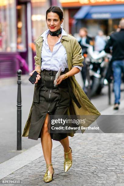 Guest wears a shirt, a skirt, gold shoes, a trench coat, a scarf choker, outside Koche, during Paris Fashion Week Womenswear Spring/Summer 2018, on...