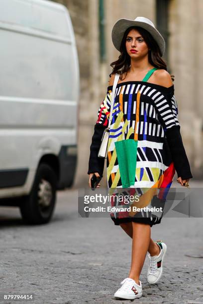 Guest wears a white hat, an off-shoulder colored dress, white sneakers, outside Koche, during Paris Fashion Week Womenswear Spring/Summer 2018, on...