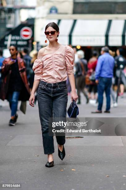 Guest wears sunglasses, an off-shoulder ruffle silk pink top, black jeans, outside Koche, during Paris Fashion Week Womenswear Spring/Summer 2018, on...