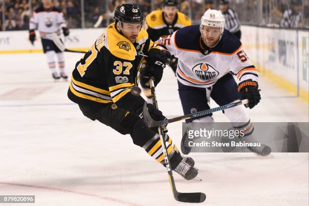 Patrice Bergeorn of the Boston Bruins fights for the puck against Mark Letestu of the Edmonton Oilers at the TD Garden on November 26, 2017 in...