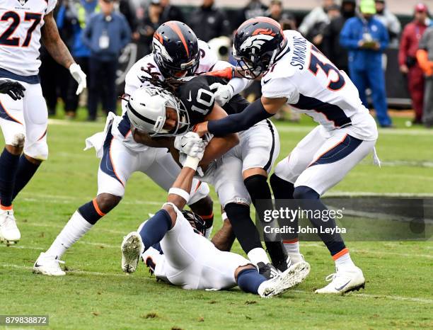 Oakland Raiders wide receiver Seth Roberts gets wrapped up by Denver Broncos defensive back Will Parks and strong safety Justin Simmons during the...