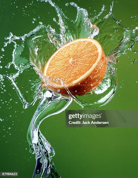 orange half splashing in water - fruit splash stock pictures, royalty-free photos & images