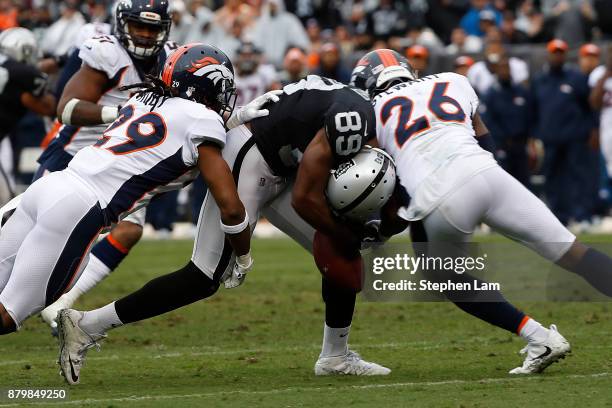 Amari Cooper of the Oakland Raiders drops the ball as he is hit by Darian Stewart and Bradley Roby of the Denver Broncos during the during the second...