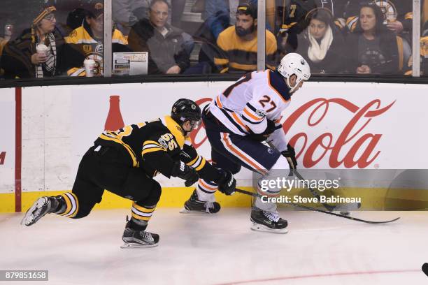 Milan Lucic of the Edmonton Oilers skates with the puck against Noel Acciari of the Boston Bruins at the TD Garden on November 26, 2017 in Boston,...