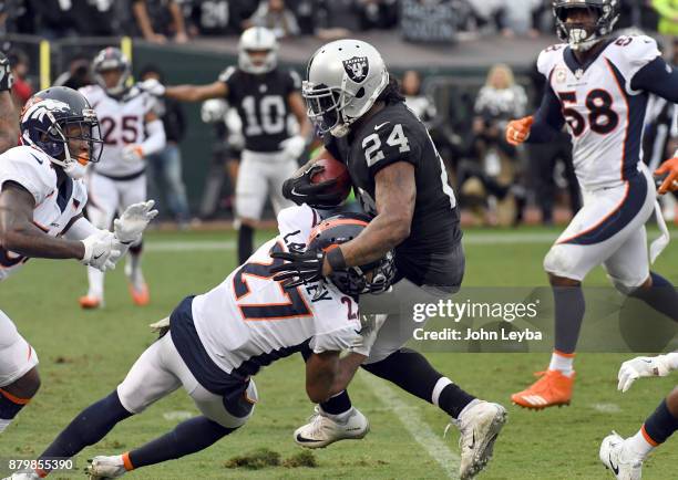 Oakland Raiders running back Marshawn Lynch gets hit by Denver Broncos cornerback Brendan Langley during the second quarter on November 26, 2017 in...