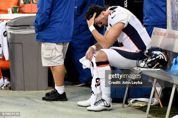 Denver Broncos training staff looks over quarterback Paxton Lynch sits dejected on the bench in the fourth quarter against the Oakland Raiders on...