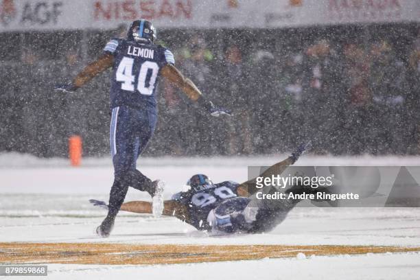 Clayton Laing of the Toronto Argonauts dives to make a snow angel after a sack against the Calgary Stampeders as teammate Shawn Lemon looks on during...