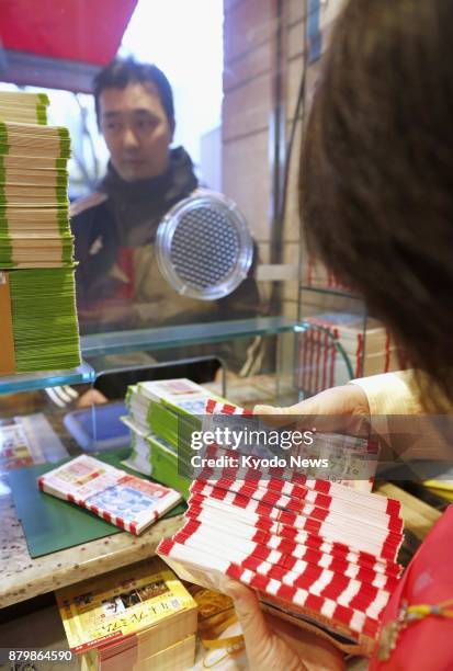 Man purchases year-end "Jumbo" lottery tickets at a lottery booth in Tokyo's Ginza district on Nov. 27, 2017. The 300-yen tickets, which give...