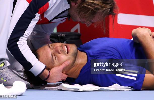 Jo-Wilfried Tsonga of France is manipulated by a trainer during day 3 of the Davis Cup World Group final between France and Belgium at Stade Pierre...