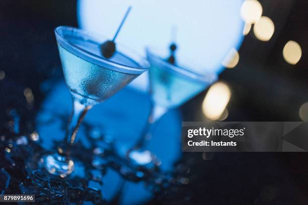 outdoors night shot of two martinis with olives, as shot in nassau. - dirty martini stock pictures, royalty-free photos & images