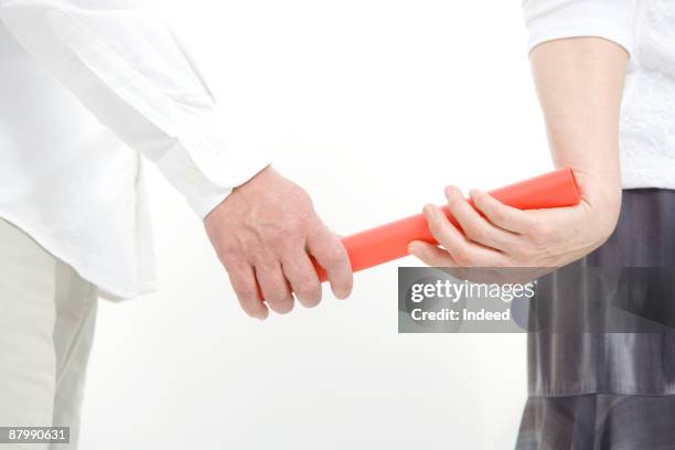 man passing baton to woman, mid section - baton-handoff stock pictures, royalty-free photos & images