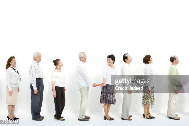 man passing baton to woman in a row - pessoas em fila imagens e fotografias de stock