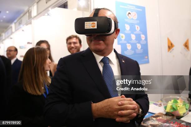 Turkish Foreign Minister Mevlut Cavusoglu watches a video by wearing a virtual reality glasses as he visits a fair booth during the opening of the...