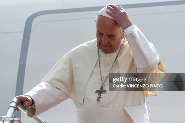 Pope Francis adjusts his skull cap as he prepares to disembark from a plane as he arrives at Yangon International Airport on November 27, 2017. -...