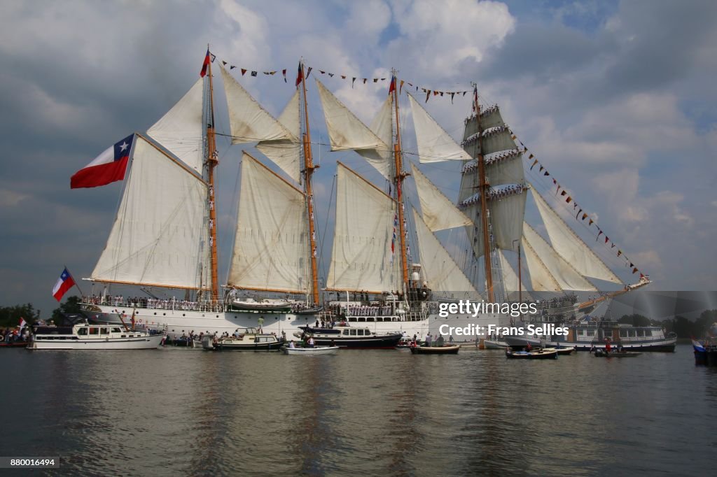 A tall ship escorted by smaller ships on its way to Amsterdam