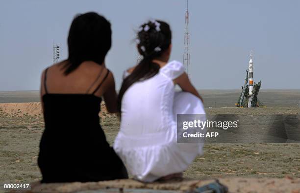 Kazakh girls watch as the Russian Soyuz TMA-15 rocket carrying Canadian astronaut Robert Thirsk, European Space Agency astronaut Frank De Winne of...