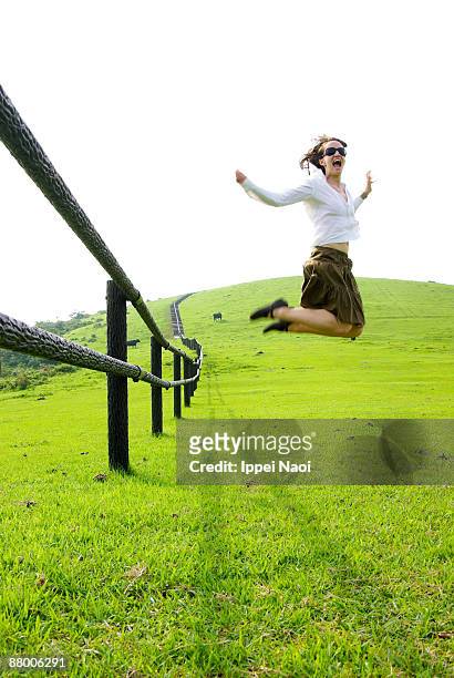 girl jumping on the green hill - okinoshima stock pictures, royalty-free photos & images