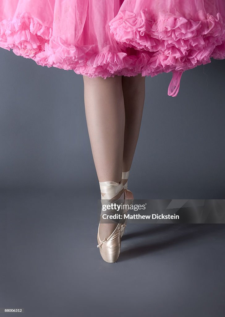 Legs of ballet dancer on point with pink tutu