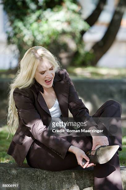 young woman looking at broken stiletto heel - woman in broken shoe heel stockfoto's en -beelden