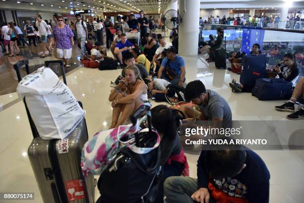 Passengers gather at the Gusti Ngurah Rai International airport in Denpasar, Bali on November 27 after flights were cancelled due to the threat of an...