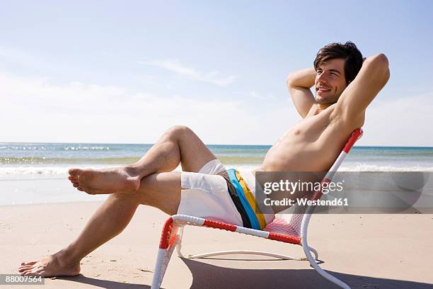 germany, baltic sea, young man relaxing in chair on beach, portrait - man on the beach relaxing in deckchair fotografías e imágenes de stock