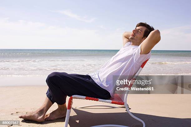 germany, baltic sea, young man on beach, portrait - deck chair 個照片及圖片檔