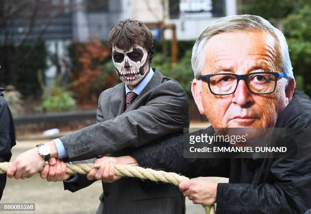Activists acting as European Commission President Jean-Claude Juncker and a Monsanto-character with their faces painted with a skull enact a...