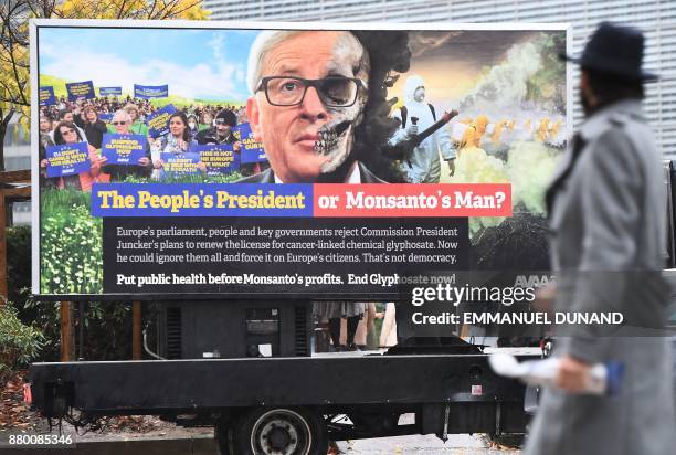 Pedestrian looks at a truck displaying a billboard featuring European Commission President Jean-Claude Juncker during an action calling for the EU...