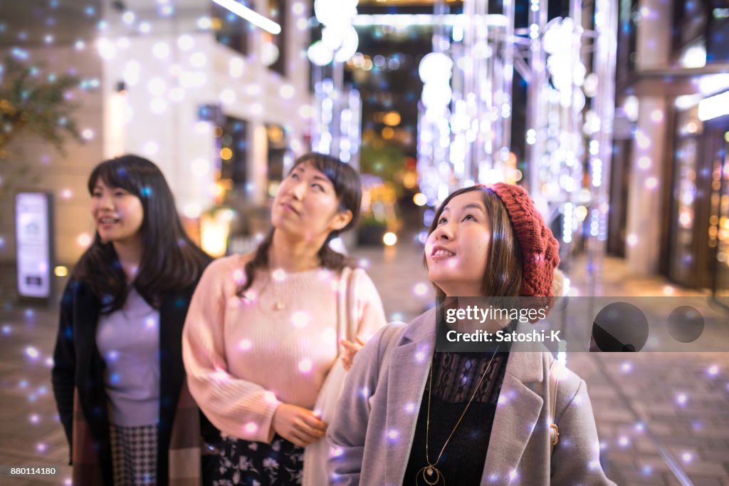 Female friends looking up in electrical snow white Christmas